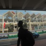 Calon penumpang berjalan dengan latar belakang pembangunan stasiun kereta tanpa masinis/automated people mover system (APMS) atau skytrain di Bandara Soetta, Tangerang, Banten, 25 Agustus 2017. Skytrain yang menghubungkan Terminal 1, 2, dan 3 di Bandara Soetta itu diharapkan akan lebih memberikan kemudahan akses antar terminal bagi penumpang maskapai penerbangan.