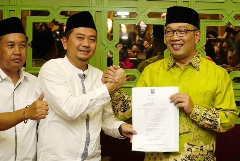 Ketua DPW PKB Jawa Barat Syaiful Huda (tengah) berjabat tangan dengan Wali Kota Bandung Ridwan Kamil (kanan) memberikan memberikan Surat Keputusan Dukungan PKB kepada Ridwan Kamil sebagai Calon Gubernur Jabar, Bandung, Jawa Barat, Senin (11/9).