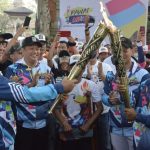 Menteri Sosial Agus Gumiwang Kartasasmita (kiri) menyulutkan api obor yang dibawa atlet Paralimpik cabang atletik I Nyoman Oka (kanan) disaksikan Ketua DPR RI Bambang Soesatyo (kedua kiri) saat Pawai Obor (Torch Relay) Asian Para Games 2018 di Denpasar, Bali, Minggu (16/9).