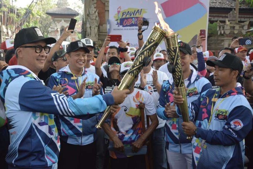 Menteri Sosial Agus Gumiwang Kartasasmita (kiri) menyulutkan api obor yang dibawa atlet Paralimpik cabang atletik I Nyoman Oka (kanan) disaksikan Ketua DPR RI Bambang Soesatyo (kedua kiri) saat Pawai Obor (Torch Relay) Asian Para Games 2018 di Denpasar, Bali, Minggu (16/9).
